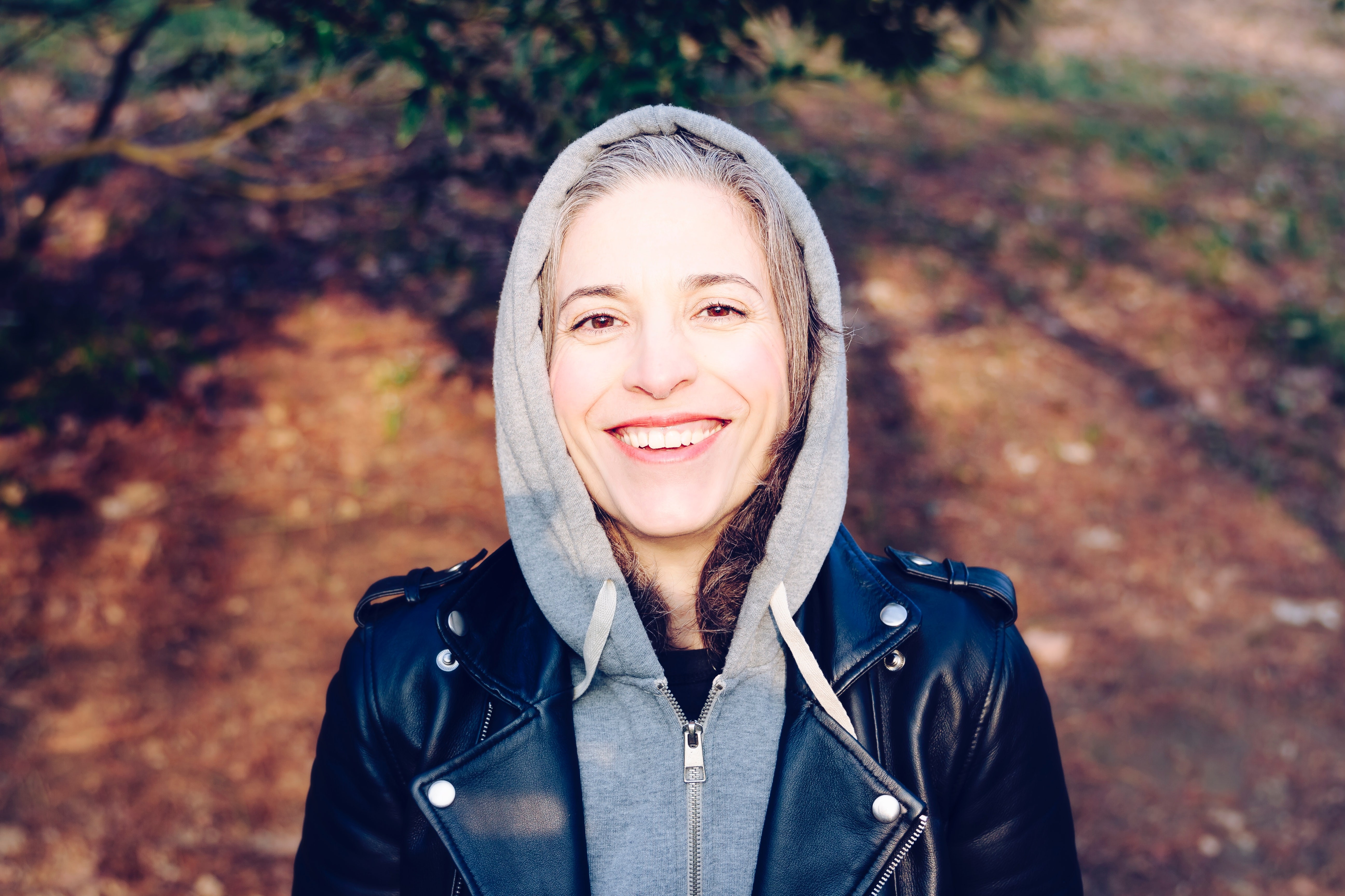 photo of a woman wearing a hoody and a leather jacket, outside in nature