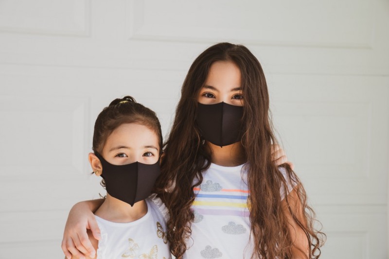 Image of a mother and daughter wearing masks, looking at the camera